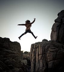 Une femme saute d'un rocher à un autre